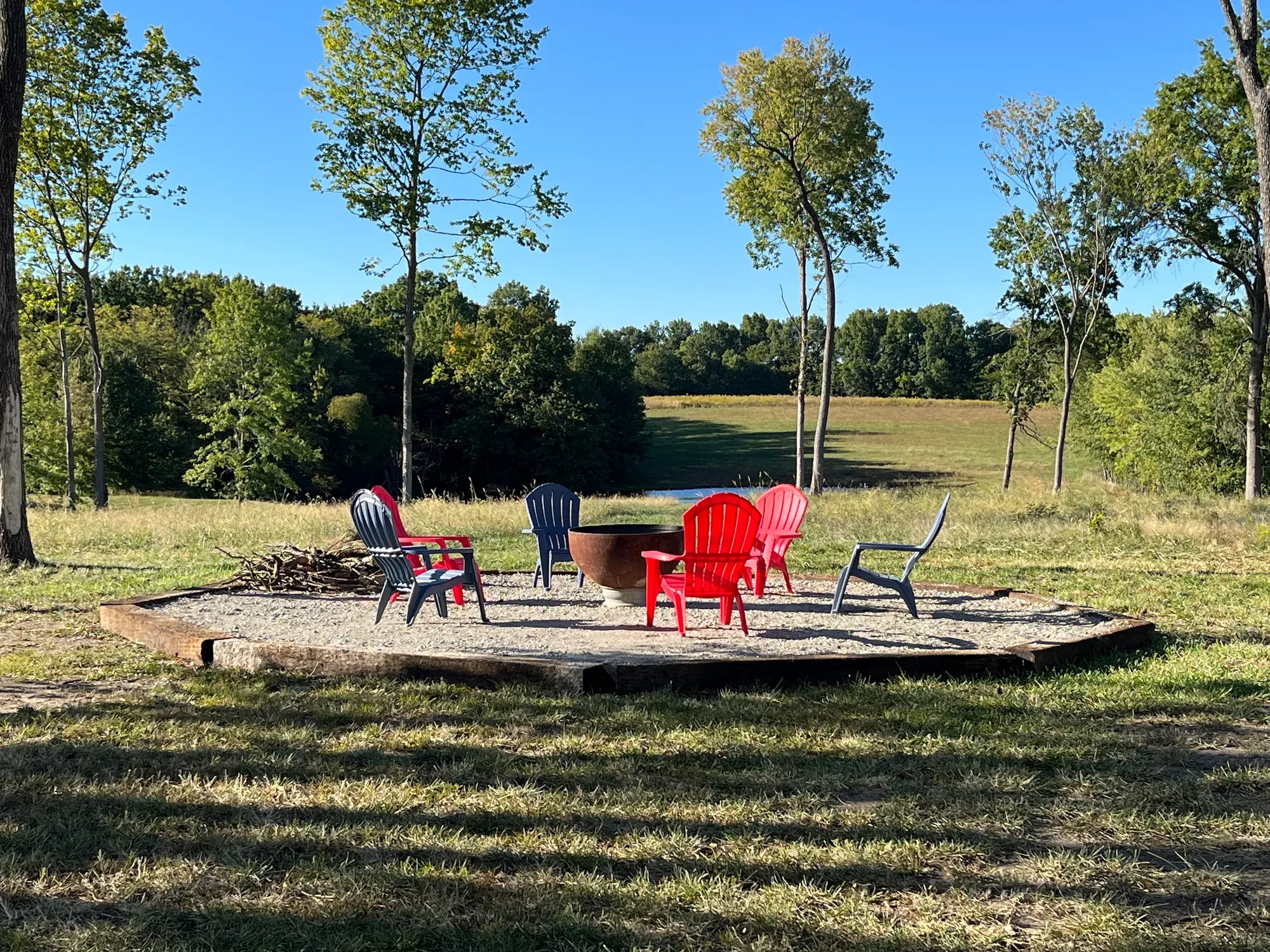 Fire pit and chairs with open fields and tree lines behind