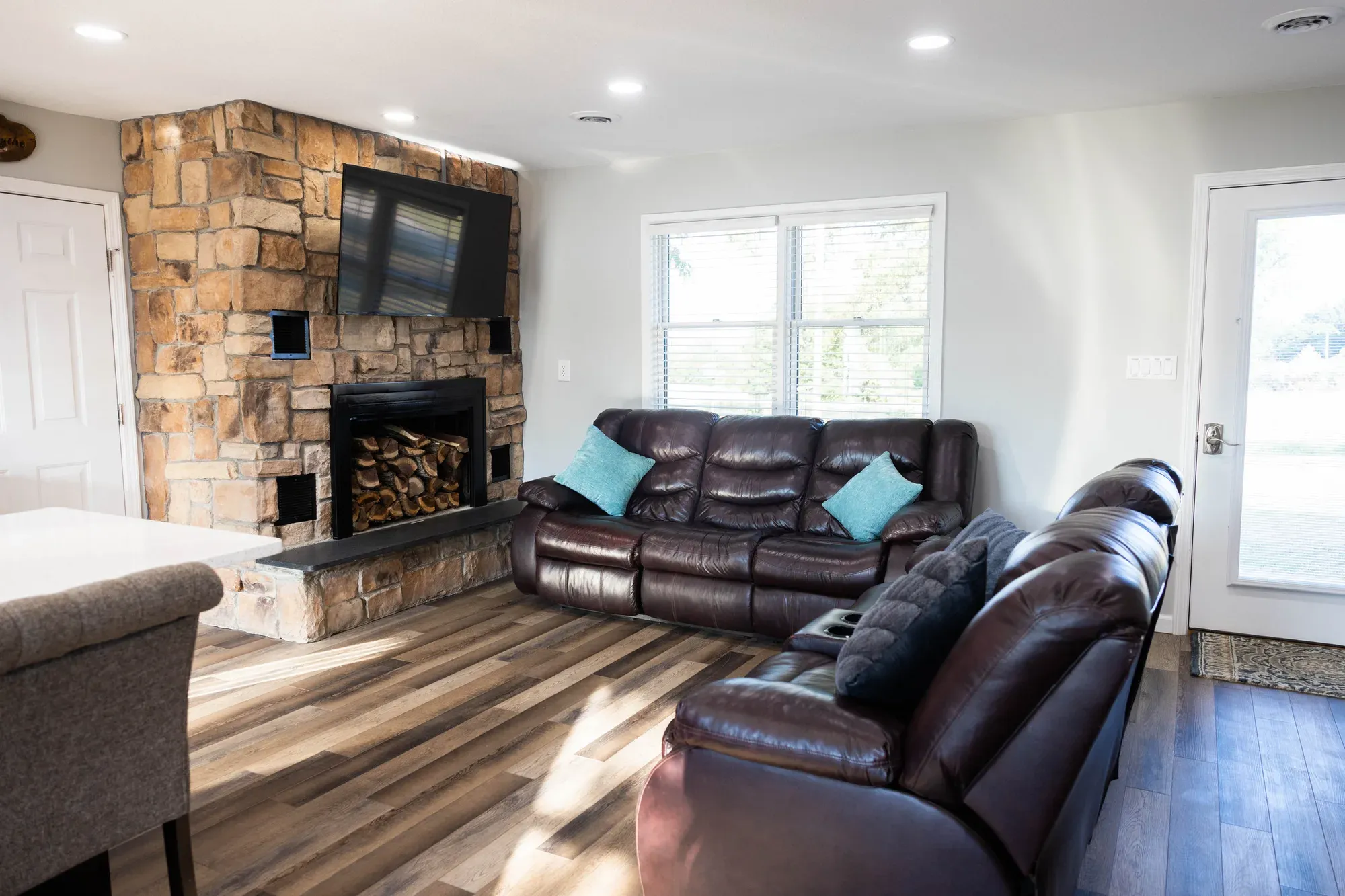 Living room with brown leather sofas and a stone accent wall with a TV